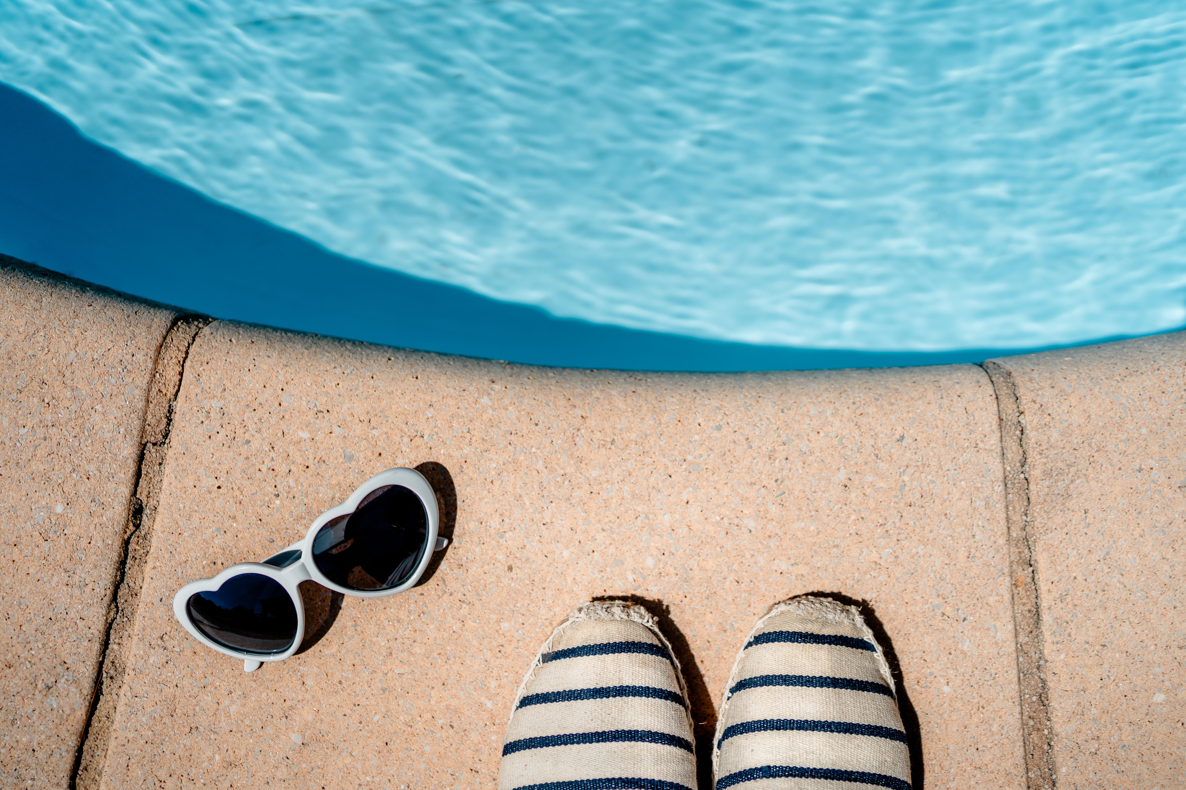 Espadrilles et lunettes au bord de la piscine
